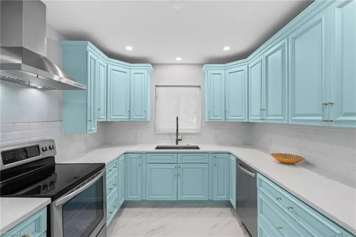 Kitchen with wall chimney exhaust hood, a sink, recessed lighting, stainless steel appliances, and marble finish floor