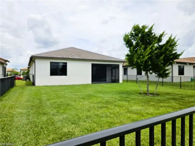 Back of house with a fenced backyard, stucco siding, and a lawn
