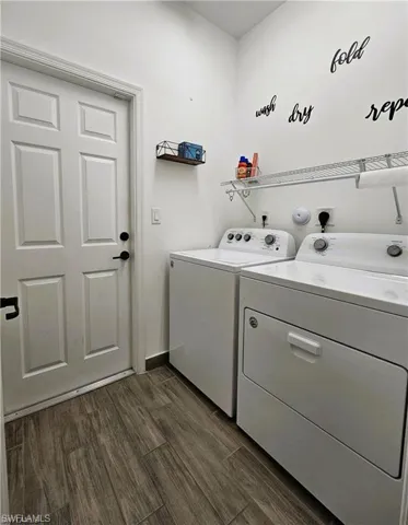 Laundry room with baseboards, washer and dryer, laundry area, and dark wood-style flooring