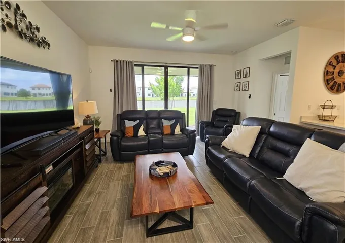 Living room with wood tiled floor, ceiling fan, and visible vents