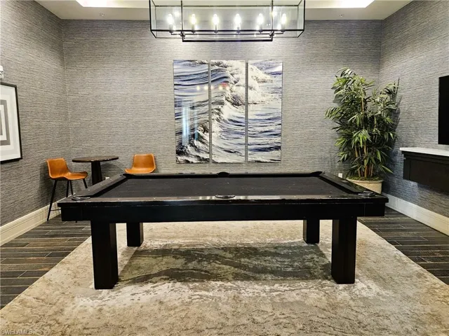 Game room with an inviting chandelier, wood finish floors, and billiards