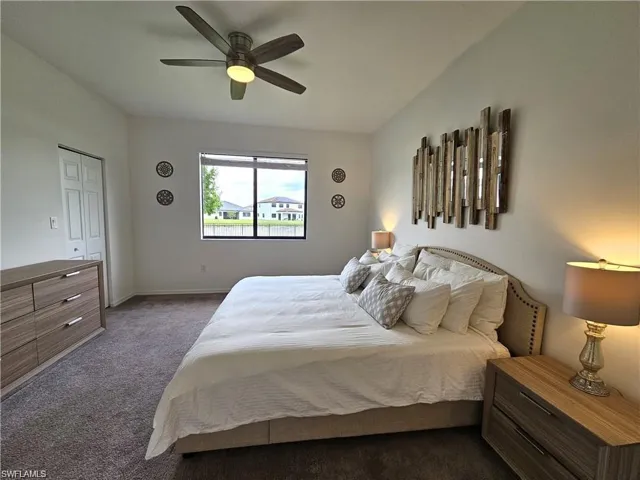 Bedroom featuring baseboards, dark colored carpet, and a ceiling fan