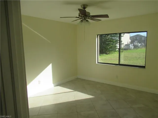 Empty room with ceiling fan and light tile patterned flooring
