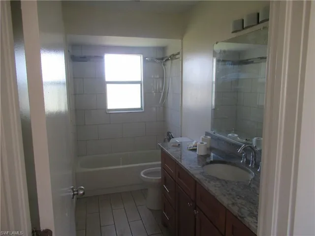 Full bathroom featuring tiled shower / bath, vanity, and toilet