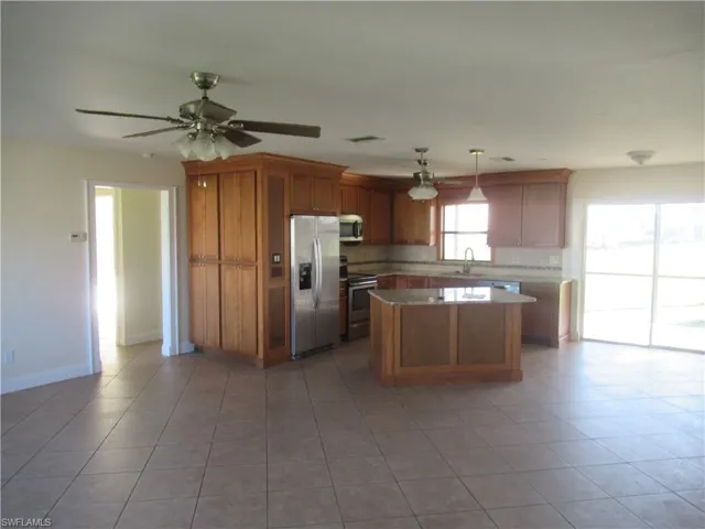 Kitchen featuring sink, a center island, stainless steel appliances, pendant lighting, and light tile patterned floors