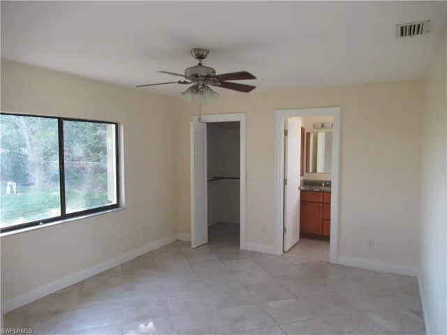 Unfurnished bedroom with a walk in closet, ensuite bathroom, a closet, and ceiling fan