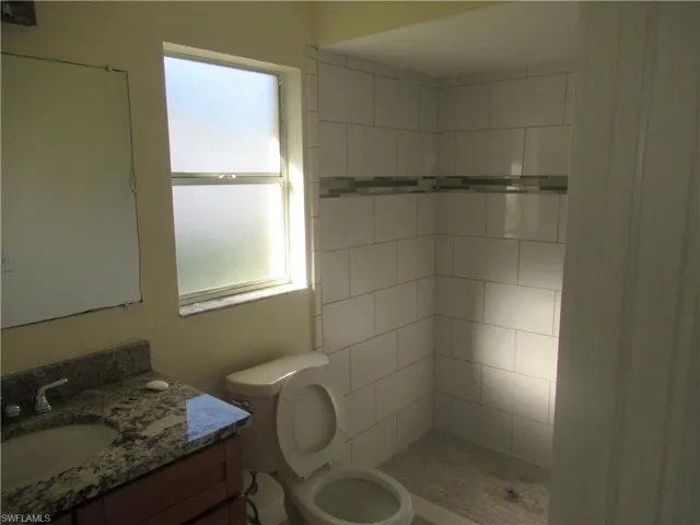 Bathroom with toilet, vanity, and a tile shower