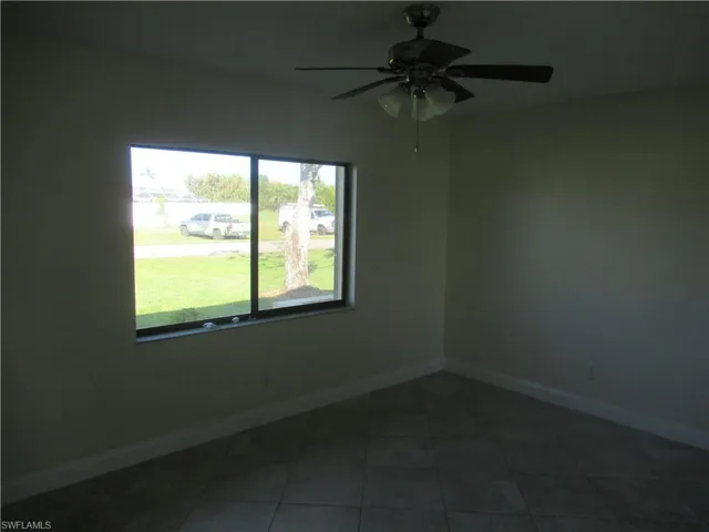 Unfurnished room with dark tile patterned floors and ceiling fan