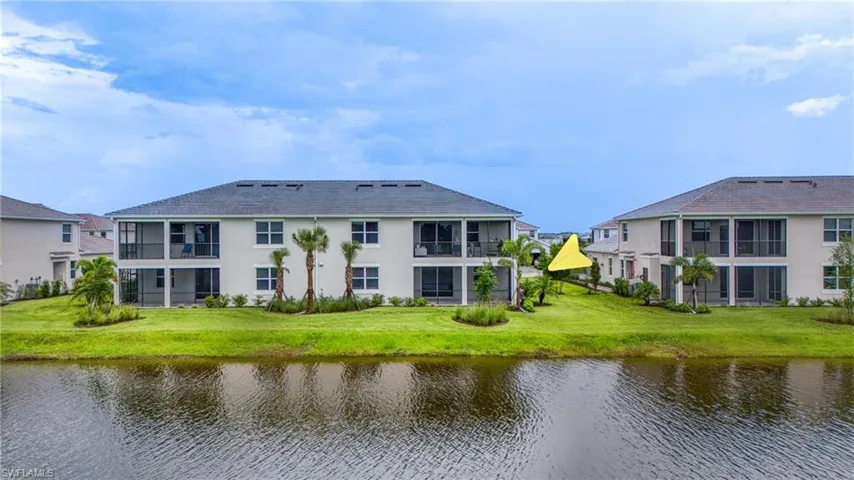 Waterfront property with screened balconies and patios, manicured lawn, and mature palm trees