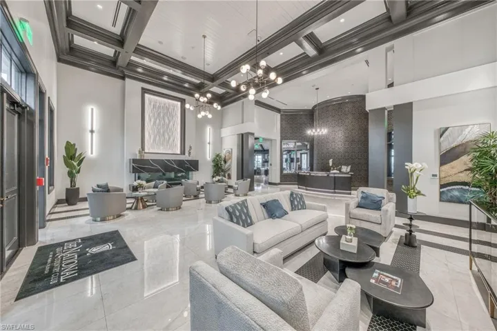 Spacious common area featuring high ceilings with decorative beams, polished tile flooring, a built-in fireplace, and a reception desk