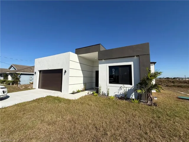 Modern home with a front lawn, concrete driveway, a garage, and stucco siding