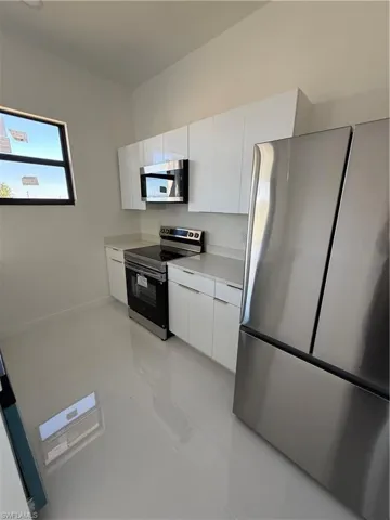 Kitchen with stainless steel appliances, white cabinetry, modern cabinets, and light tile patterned flooring