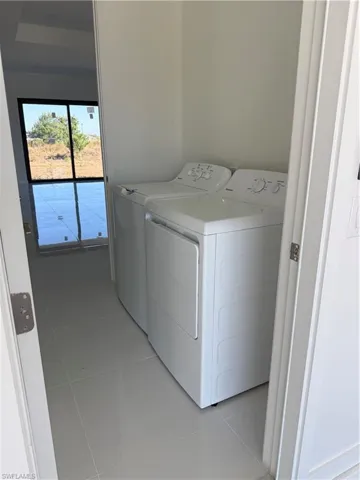 Laundry area with light tile patterned flooring and washer and dryer