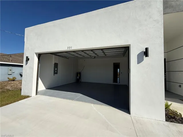 Garage featuring water heater, driveway, and electric panel