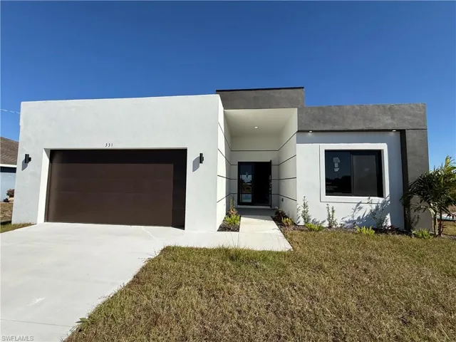 Contemporary house featuring an attached garage, stucco siding, concrete driveway, and a front lawn