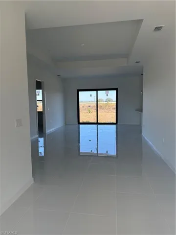 Empty room with a raised ceiling and light tile patterned flooring
