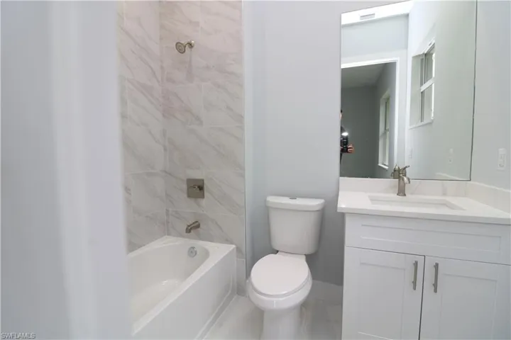 Full bathroom with vanity, toilet, tiled shower / bath, and tile patterned flooring