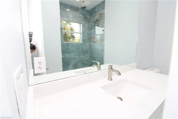 Bathroom featuring tiled shower, toilet, and vanity
