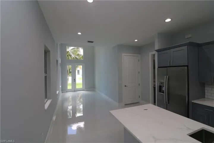 Kitchen featuring french doors, stainless steel refrigerator with ice dispenser, light stone counters, and backsplash
