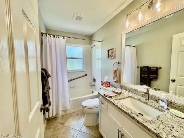 Full bath featuring visible vents, shower / tub combo with curtain, tile patterned flooring, vanity, and toilet