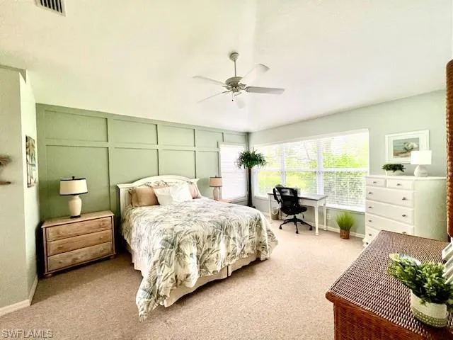 Bedroom featuring carpet, a decorative wall, and a ceiling fan