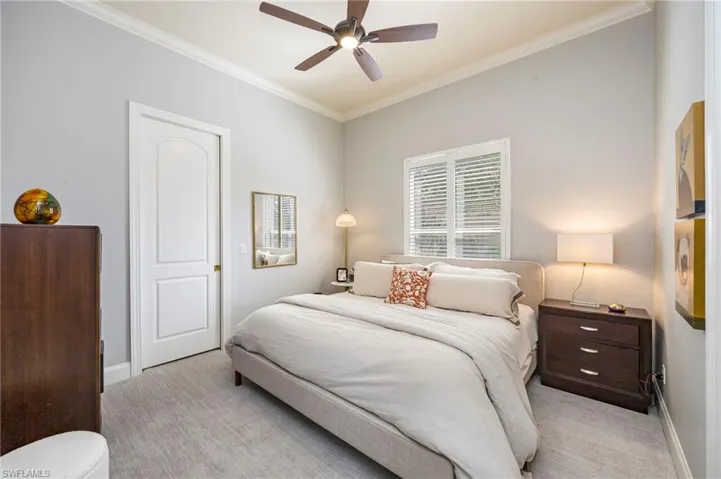 Carpeted bedroom featuring ornamental molding and ceiling fan