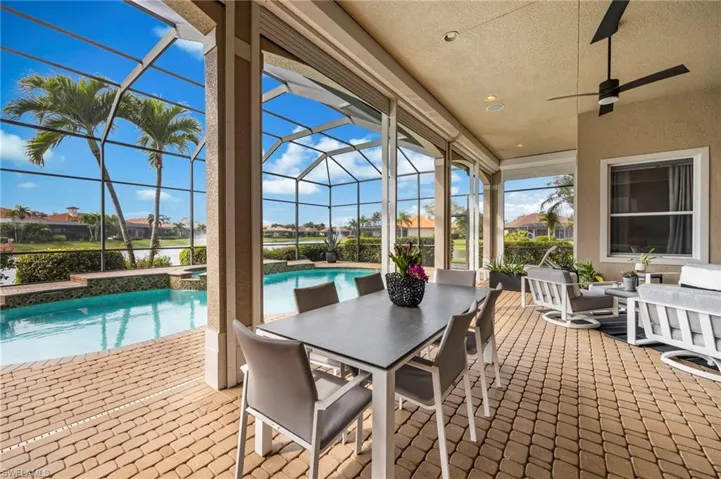 View of patio / terrace featuring a sunroom, outdoor dining space, a ceiling fan, glass enclosure, and a residential view