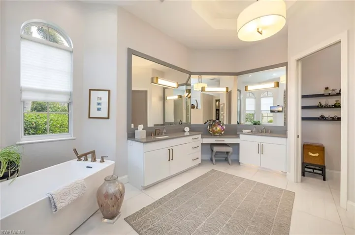 Bathroom with a soaking tub, double vanity, and healthy amount of natural light