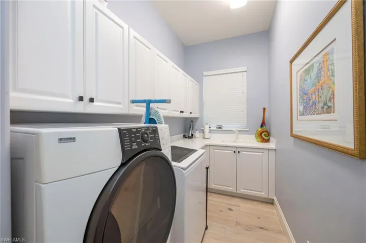 Laundry room with light wood-style flooring, cabinet space, and washer and dryer
