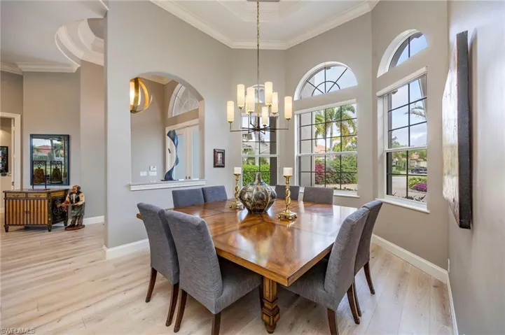 Dining area featuring light wood-style floors, crown molding, a towering ceiling, and a chandelier