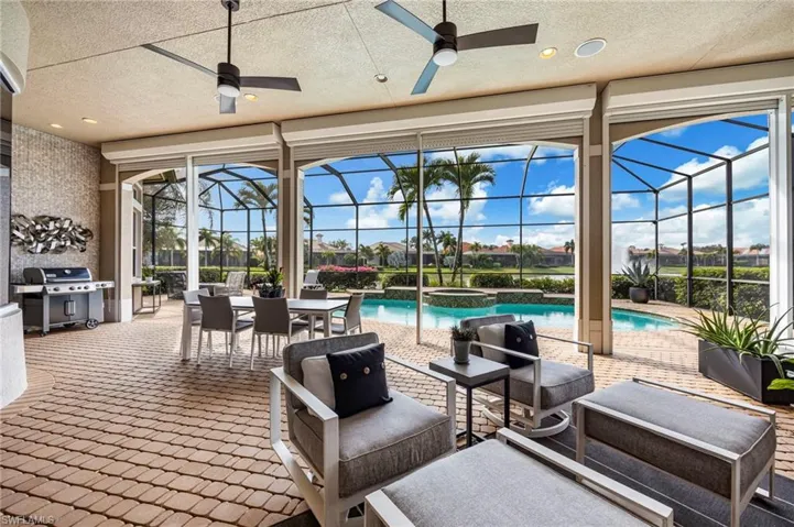 View of patio with a sunroom, a pool with connected hot tub, outdoor dining area, grilling area, and glass enclosure