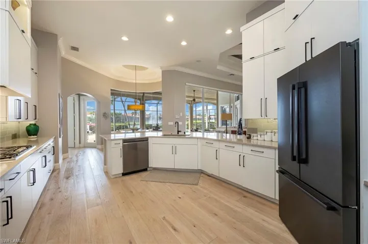 Kitchen featuring backsplash, stainless steel appliances, white cabinets, a peninsula, and ornamental molding