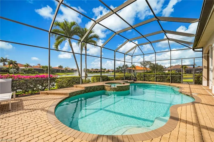View of swimming pool featuring a sunroom, glass enclosure, a pool with connected hot tub, a residential view, and a water view