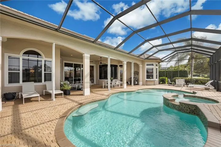 View of swimming pool featuring glass enclosure, a patio area, a pool with connected hot tub, and a sunroom