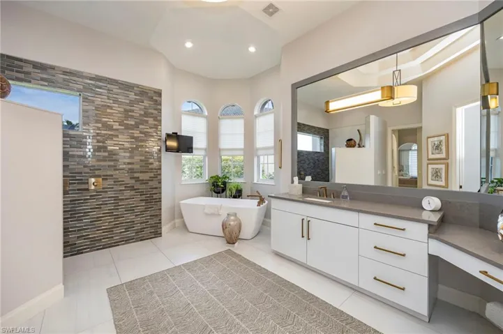 Full bath featuring walk in shower, vanity, a freestanding tub, light tile patterned floors, and recessed lighting