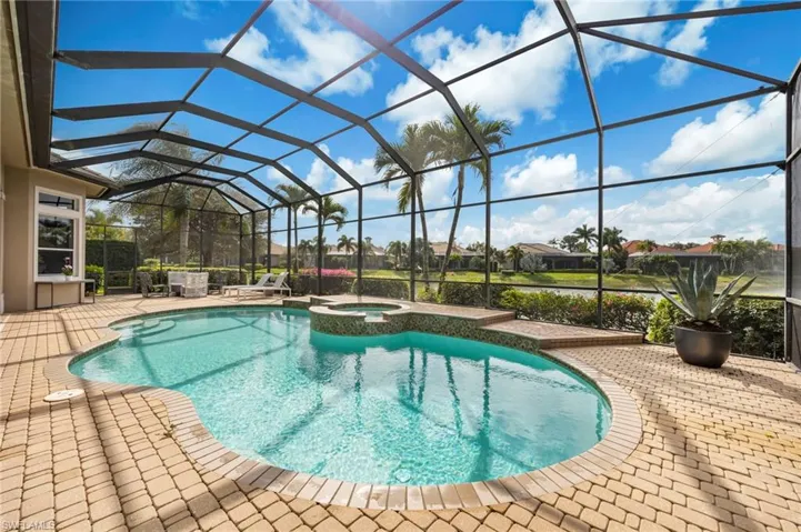 View of pool featuring a sunroom, a patio area, a lanai, a pool with connected hot tub, and a residential view