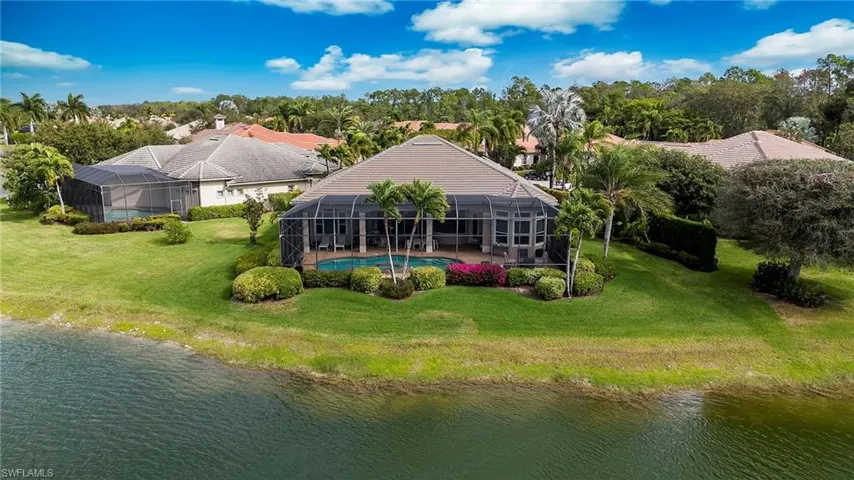 Back of property with a sunroom, glass enclosure, view of wooded area, and a water view