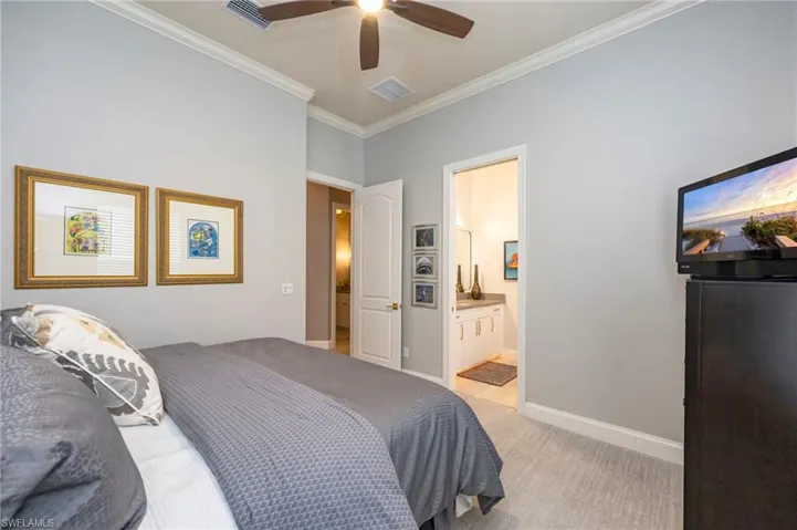 Bedroom with light carpet, ornamental molding, and a ceiling fan