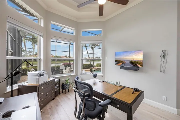 Office space with ornamental molding, light wood finished floors, a raised ceiling, and ceiling fan