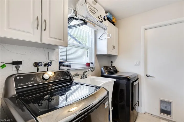 Laundry area featuring washing machine and clothes dryer, visible vents, and cabinet space