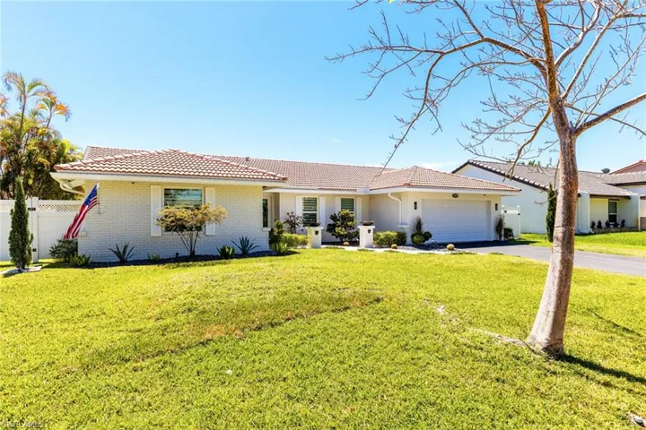 View of front facade with a front yard, fence, a garage, aphalt driveway, and a tiled roof