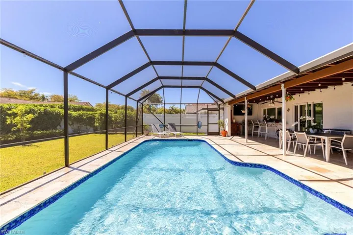 View of pool with a lanai, a patio area, a lawn, and ceiling fan