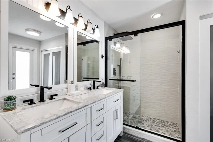 Full bathroom featuring a sink, double vanity, and a shower stall