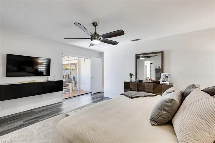Bedroom with visible vents, a ceiling fan, a textured ceiling, wood finished floors, and baseboards