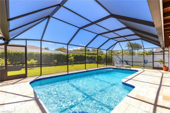 View of pool featuring glass enclosure, a patio, a lawn, and a fenced in pool