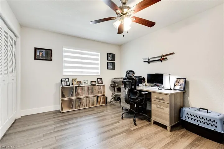 Office area with baseboards, light wood-style floors, and a ceiling fan