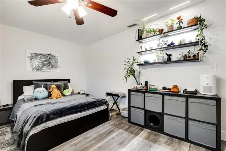 Bedroom with visible vents, wood finished floors, and a ceiling fan
