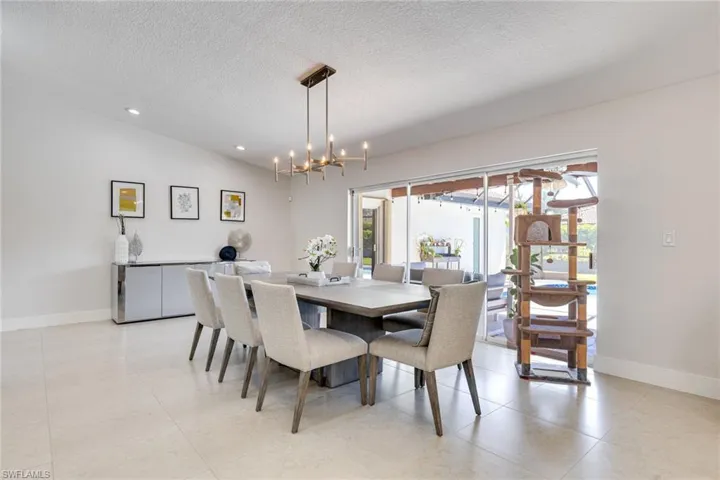 Dining room with baseboards, lofted ceiling, a textured ceiling, and an inviting chandelier