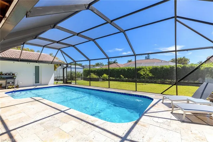 Outdoor pool featuring glass enclosure, a patio, and a lawn