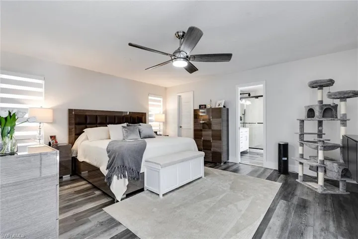 Bedroom featuring wood finished floors, ensuite bathroom, and ceiling fan